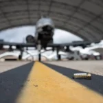 A bolt fallen on the tarmac in front of an aircraft hangar, which is considered foreign object debris.