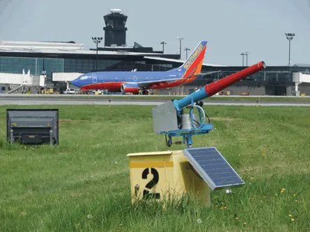 Propane cannon placed on the grass patch of an airport.